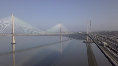 Aerial-footage-of-the-old-Forth-Road-Bridge-and-the-new-Queensferry-Crossing-Bridge-on-a-sunny-day-at-South-Queensferry-in-West-Lothian,-Scotland