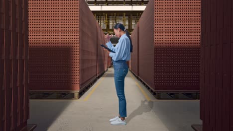 full body side view of asian female with her tablet with red brick packed in stacks are stored, she is nodding her shead with dissapionted