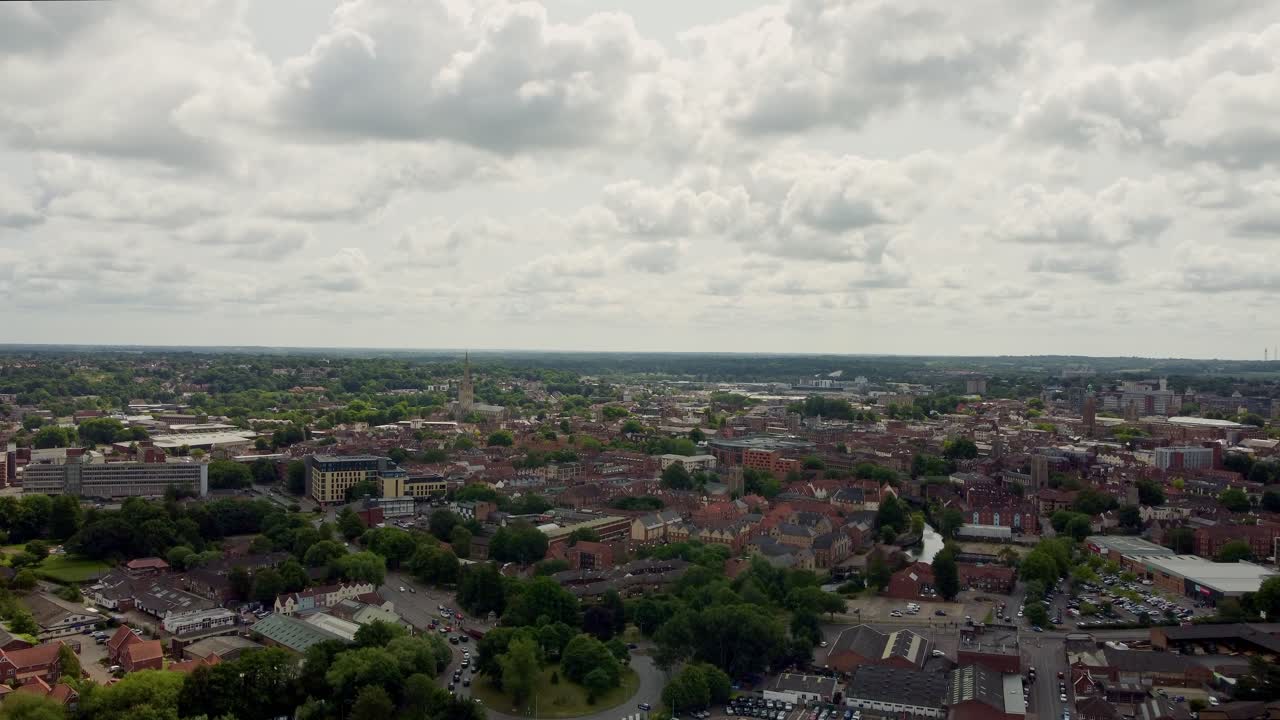 Drone video raising up over Norwich City in Norfolk. Captured on a slightly cloudy day and shows the skyline of commercial buildings, residential homes and flats and greenery mixed in-between.