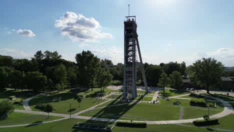 Historical-President-mine-shaft-during-a-beautiful-summer-day-surrounded-by-lush-greenery,-grass,-and-trees-under-a-blue-sky