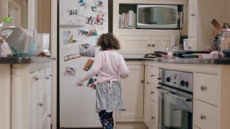 happy little girl dancing in kitchen having fun doing funny dance moves enjoying weekend at home