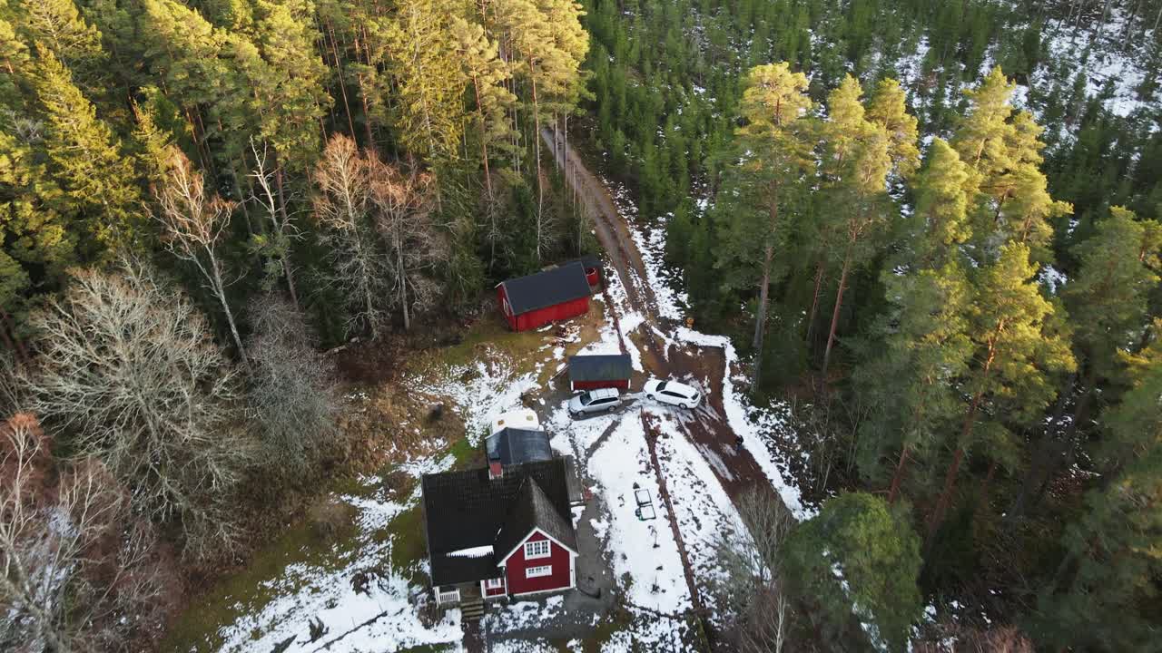 Beautiful aerial of a stunning red cabin in the Swedish countryside surrounded by forests