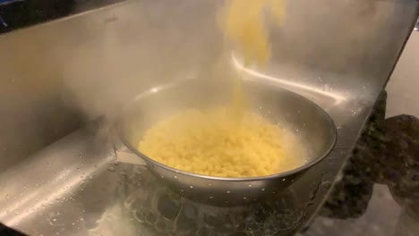 pouring boiled pasta water over sink