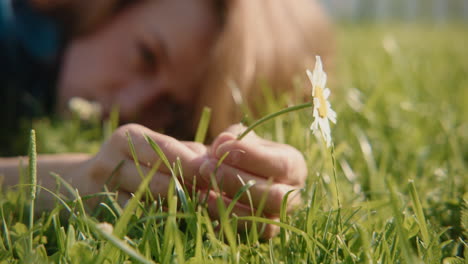 person lying in grass holding a daisy