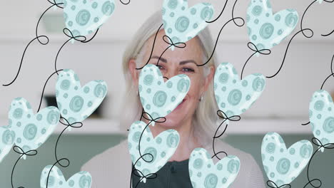 múltiples iconos de globos en forma de corazón en un patrón sin costuras contra una mujer caucásica mayor sonriendo