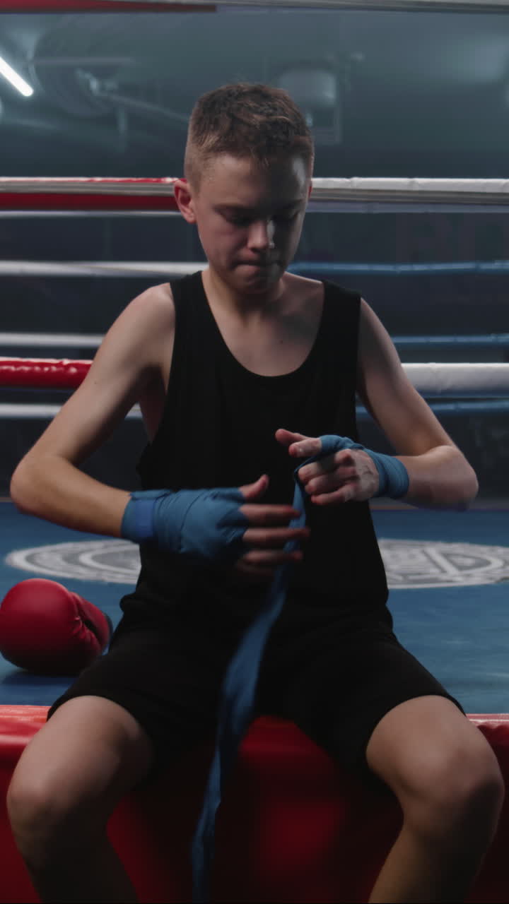 Young boxer wrapping hands in boxing ring