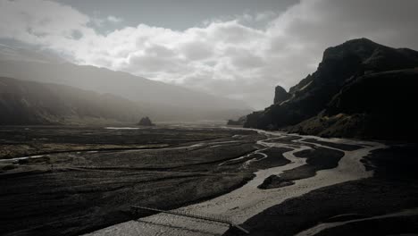 Dramatic-aerial-thor-valley,-glacial-river-flowing-through-black-volcanic-scenery-bridges-for-river-crossings,-thorsmörk-Iceland