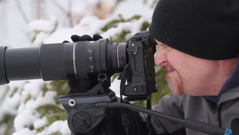 Middle-age-male-photographer-with-hat-and-gloves-uses-long-camera-lens