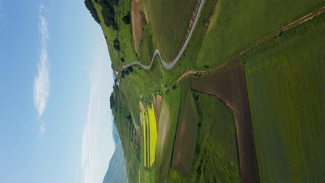 Spectacular-vertical-aerial-drone-shot-of-Norcia-rural-landscape-with-winding-roads-and-open-fields-during-daytime