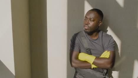 cleaning man resting and leaning on the wall while looking at camera inside an office building