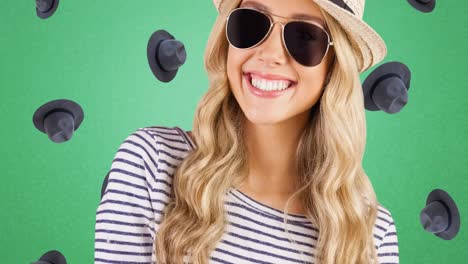 Animation-of-smiling-caucasian-woman-with-hat-and-sunglasses-over-falling-hats-on-green-background