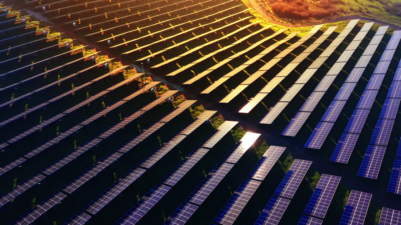 High angle view of solar panel installations organized in diagonal rows during sunset. Golden sunlight illuminating the edges of the frames