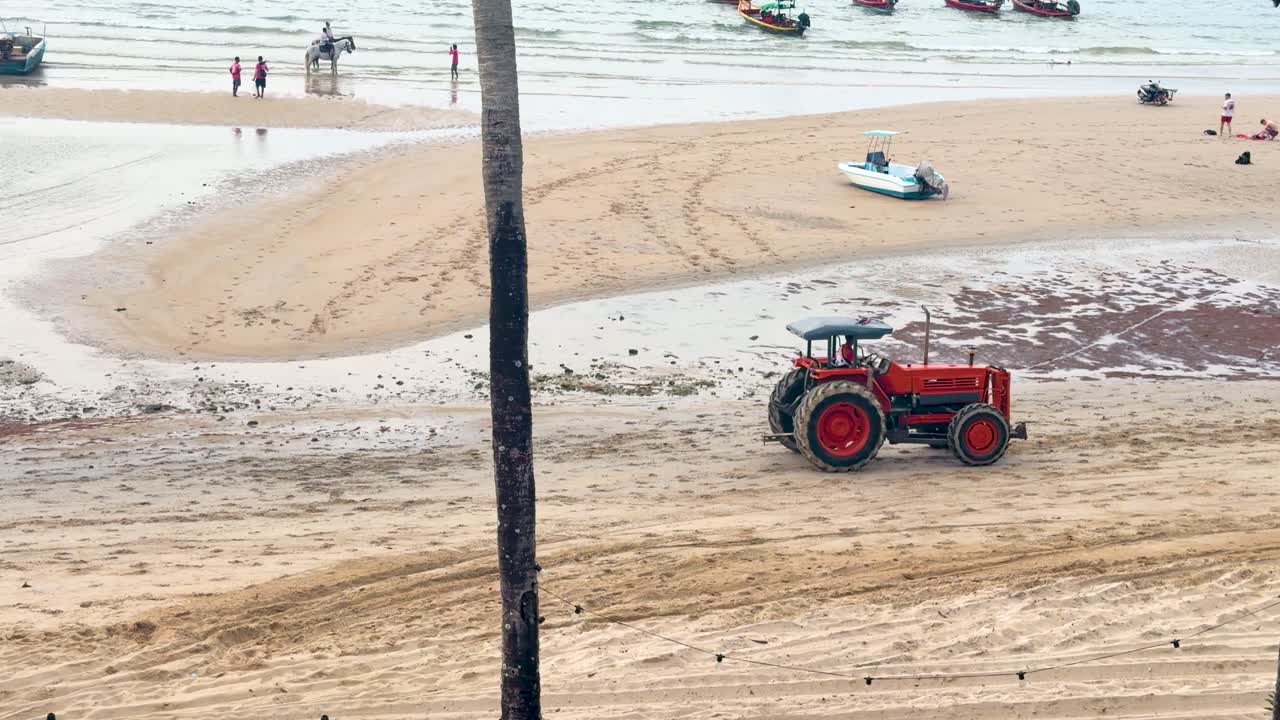 Un trattore rosso attraversa una spiaggia sabbiosa durante la bassa marea a Phuket, Thailandia