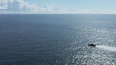 speedboat cruising through shimmering blue ocean water, aerial tracking shot