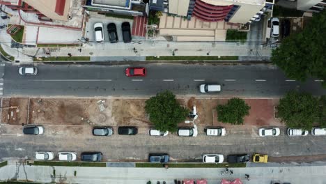 Vista-Superior-De-Pájaro-Toma-Aérea-De-Drones-De-Una-Pequeña-Intersección-De-Calles-De-La-Ciudad-En-La-Ciudad-Capital-De-La-Playa-Tropical-De-Joao-Pessoa,-Paraiba,-Brasil-Con-Peatones-Y-Autos-Pasando