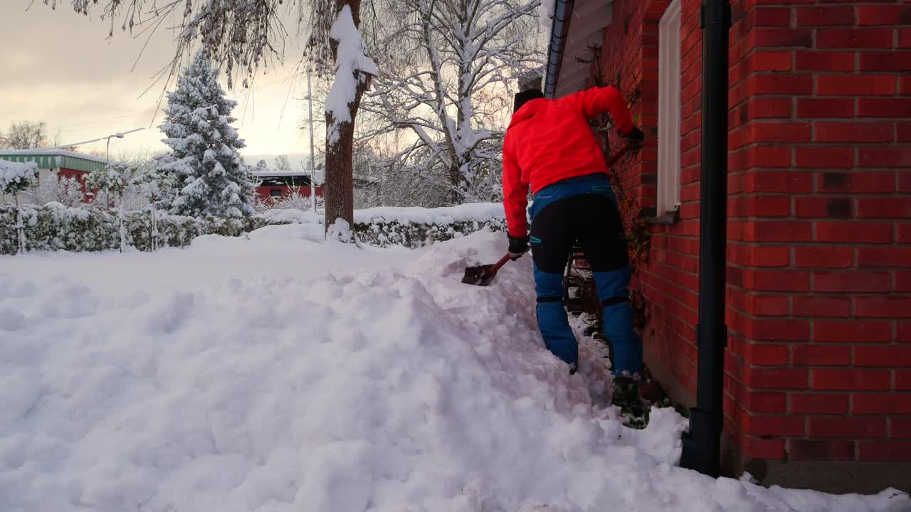 Mand kæmper med at skovle sne væk fra sit hus efter kraftigt snefald.