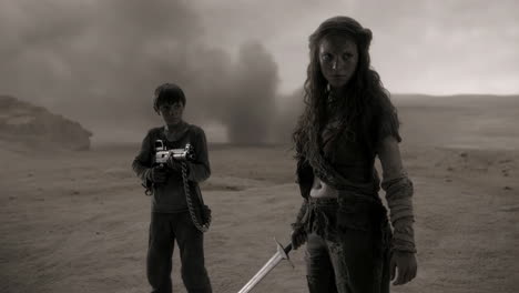 a female warrior and a boy stand in a desolate, post-apocalyptic landscape
