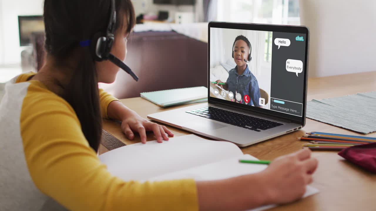 Schoolgirl using laptop for online lesson at home, with her colleague and web chat on screen