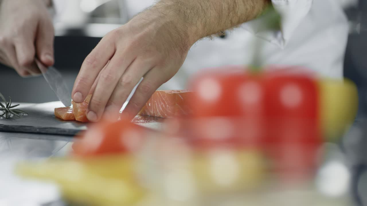 Chef cutting fish at professional kitchen. Closeup chef hands slicing salmon