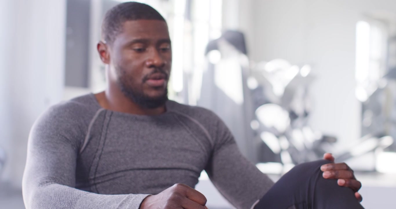 African American man in top doing rowing starting hunched engaging core finishing set on gym mat