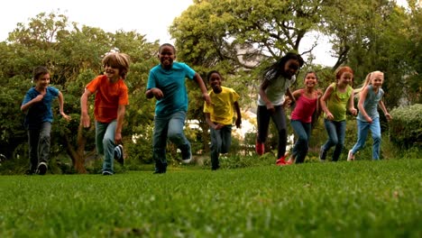 alumnos lindos corriendo en el césped fuera de la escuela