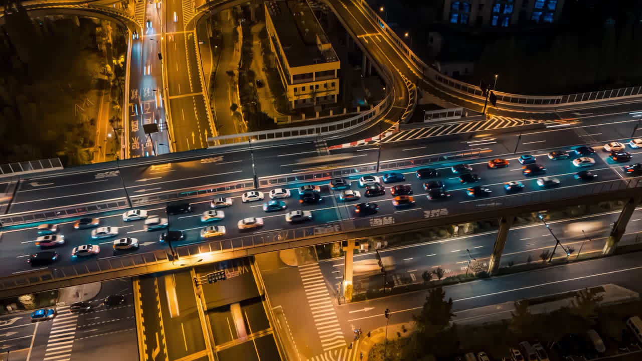 Time-lapse city night scene intersection traffic flow suburban intersection from above. Modern green traffics crossing from aerial drone. Cars, trucks and scooters crossing a busy traffic light