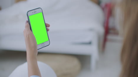 Mujer-Usando-Y-Mirando-La-Pantalla-Verde-Del-Teléfono-Inteligente-En-Casa.-La-Joven-Sostiene-Un-Teléfono-Inteligente-Con-Pantalla-Verde-Por-La-Noche.