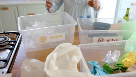 senior biracial woman segregating waste at home, slow motion