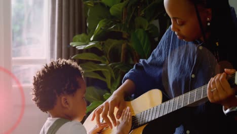 Animation-of-light-flashing-over-african-american-mother-and-son-playing-guitar