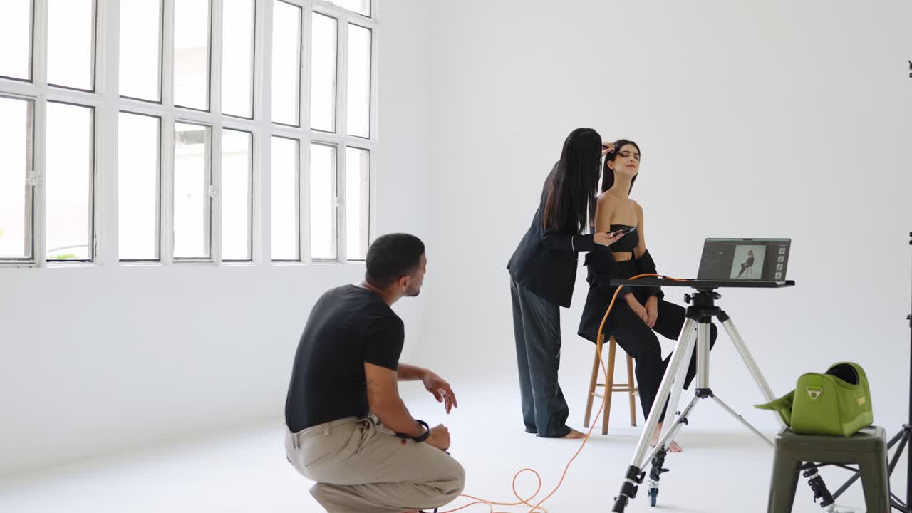 Fashion shoot with model, makeup artist, and photographer in a studio