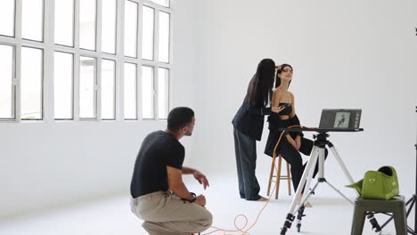 fashion shoot with model, makeup artist, and photographer in a studio