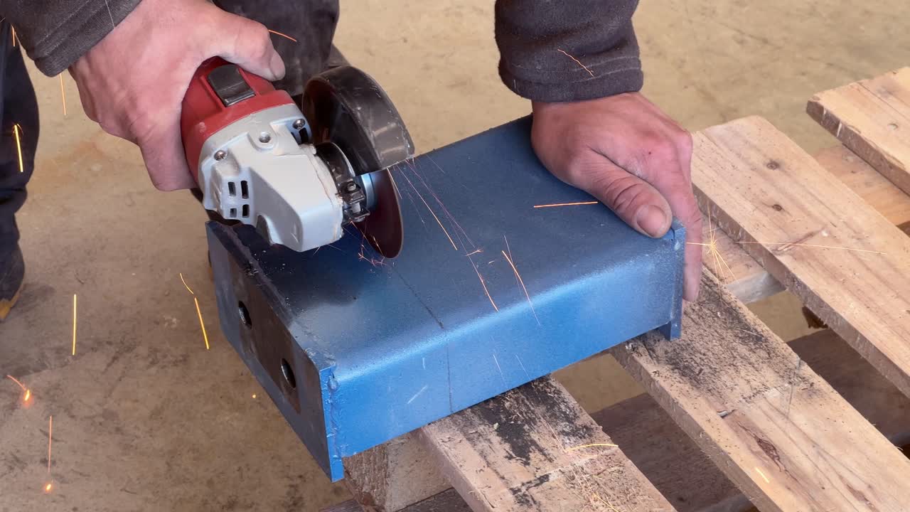 close-up of a man's hands without protective gloves cutting a metal part with an angle grinder, and sparks are flying