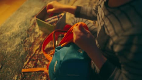 young boy packing a backpack with clothes and sweets at night in a hurry going on an adventure