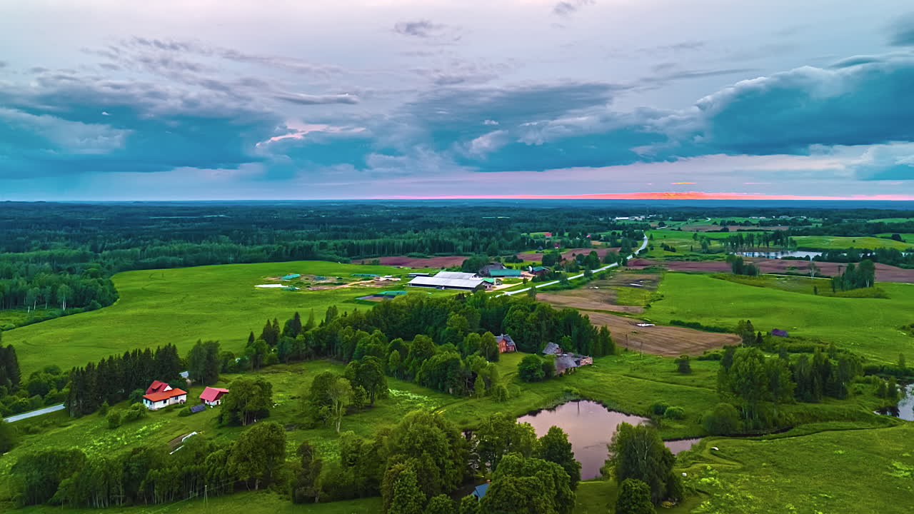 Timelapse of fast moving white clouds over bright rural fields in daylight, aerial hyperlapse over farmland