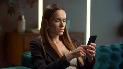 Focused-businesswoman-using-smartphone-at-remote-workplace.