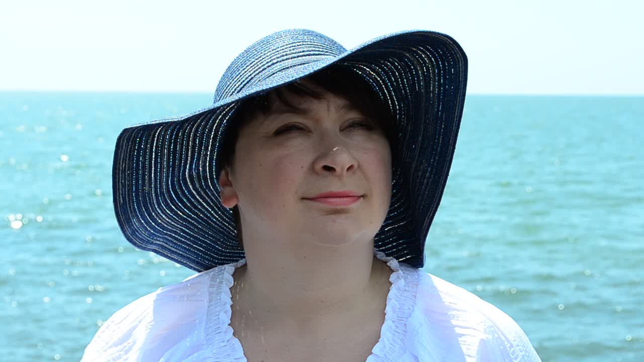 海を背景にした少女。帽子をかぶった少女