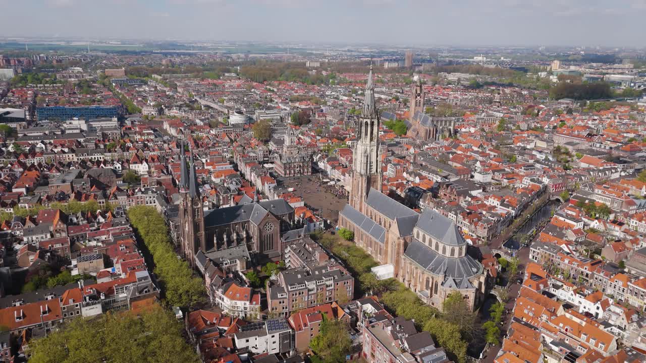 Captivating drone view of Nieuwe Kerk in Delft surrounded by tightly packed Dutch houses and winding streets, showcasing rich architectural heritage.