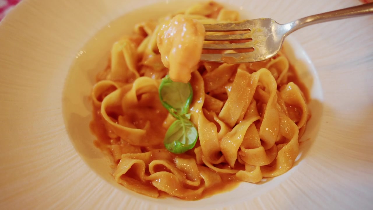 Tagliatelle fresche impiattate elegantemente con salsa di pomodoro, catturate con luce naturale soffusa.