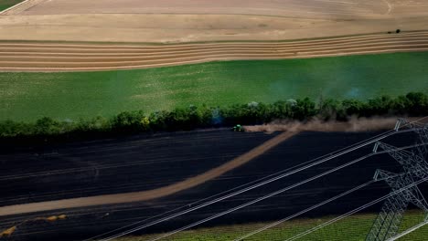 Aerial-View-Of-A-Farm-Tractor-Driving-Across-Burned-Grain-Fields