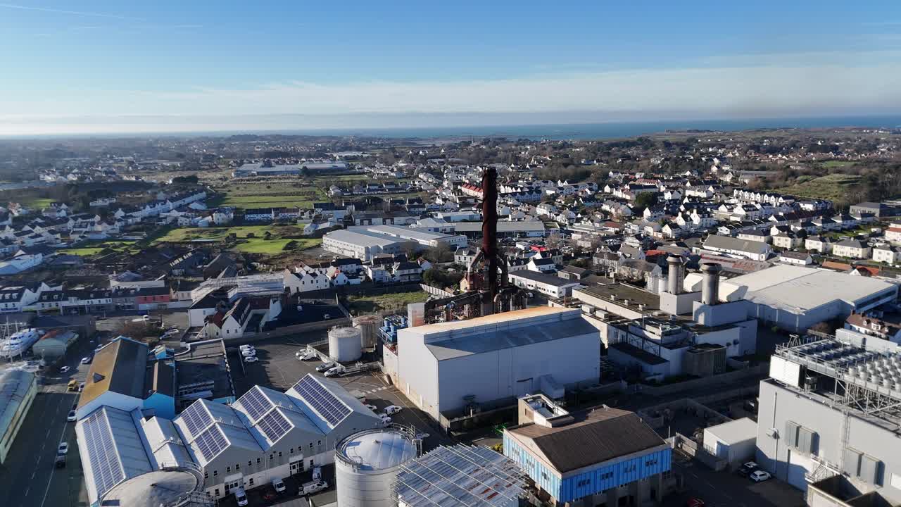Guernsey drone flight over Industrial zone in St Sampsons pulling back from power station in bright late afternoon sunlight with blue sky and full perspective of area
