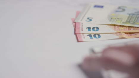 nahaufnahme einer währungsaufnahme von der hand, die auf der computertastatur tippt, mit euro-banknoten im hintergrund