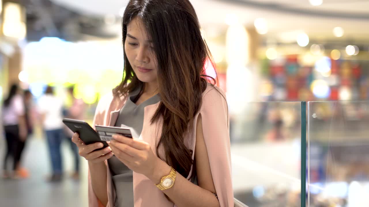 아시아 여성들은 휴대전화를 사용하고, 백화점에서 신용카드를 구입합니다.