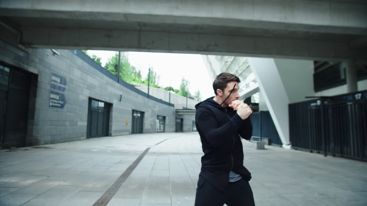 boxeador entrenando un puñetazo en una calle urbana. retrato de boxeador masculino boxeando al aire libre