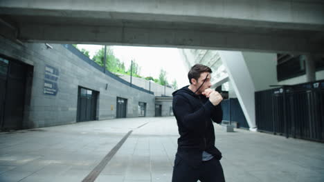 Boxer-man-training-punch-on-urban-street.-Portrait-fighter-male-boxing-outdoor