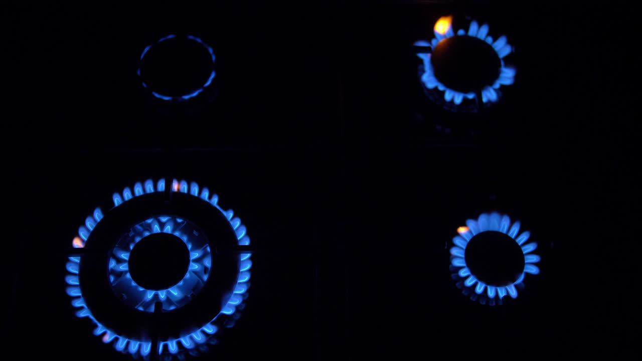 가스 스토브가 켜지고 꺼지고 파란 불꽃이 어 속에서 불타고 있습니다.