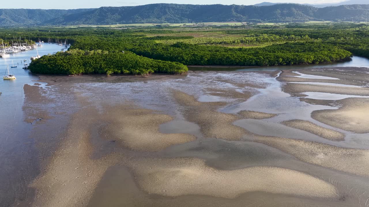 Drone footage captures the serene Daintree River, showcasing sandbanks and lush mangroves under bright daylight in Port Douglas