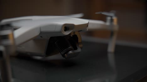 video cinematográfico de primer plano de un dron iluminado con una luz suave desde arriba y luces naranjas en el fondo, filmado en 4k con movimiento de cámara
