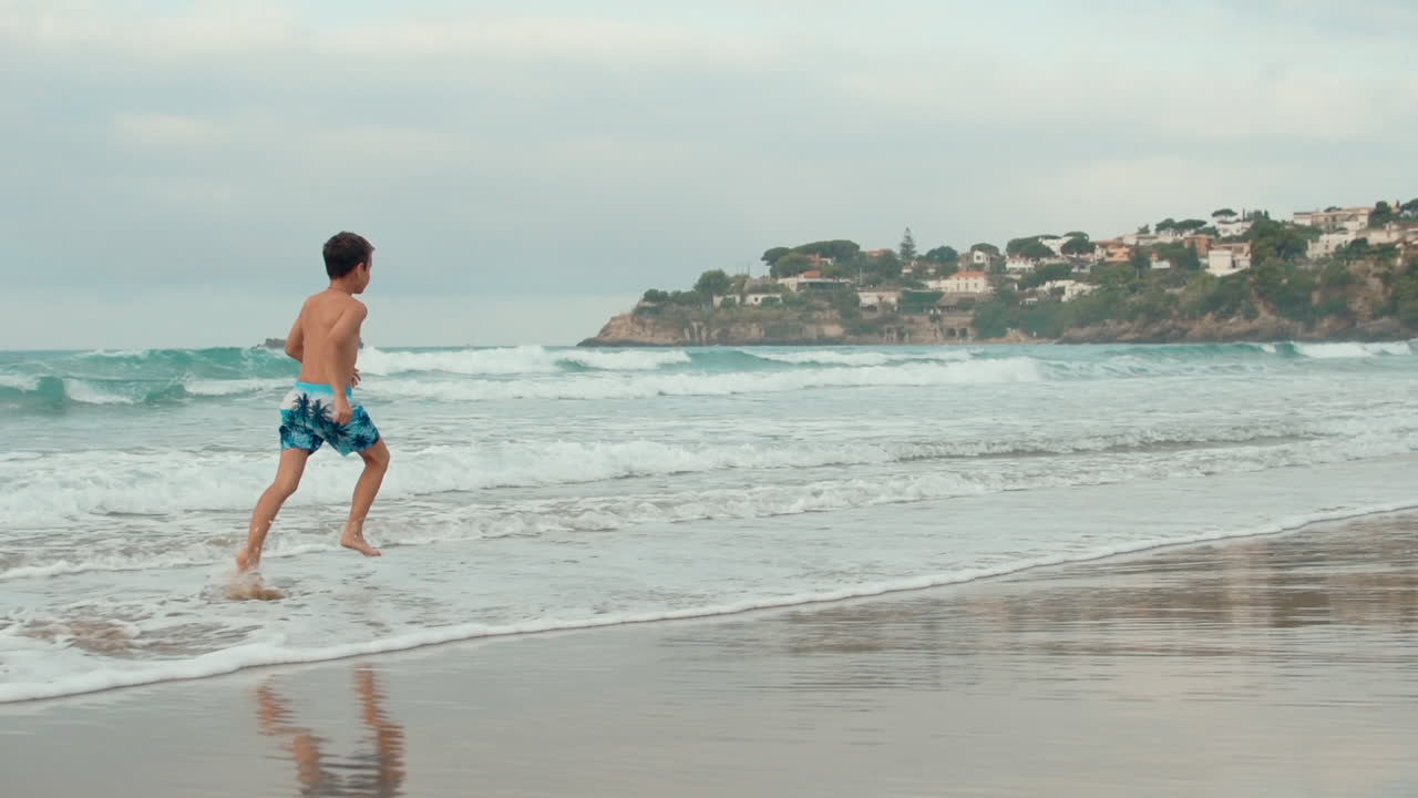 niño activo descansando en la costa. adolescente feliz corriendo en la playa de arena.