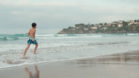 Aktiver-Junge,-Der-Sich-An-Der-Küste-Ausruht.-Glücklicher-Teenager,-Der-Am-Sandstrand-Läuft.