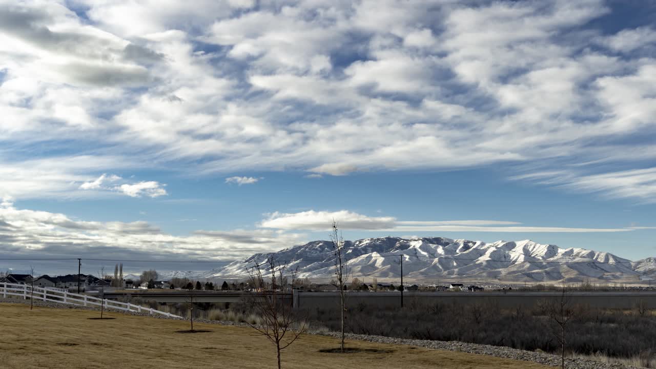 cloudscape sobre una montaña nevada distante a través del valle urbano - lapso de tiempo estático